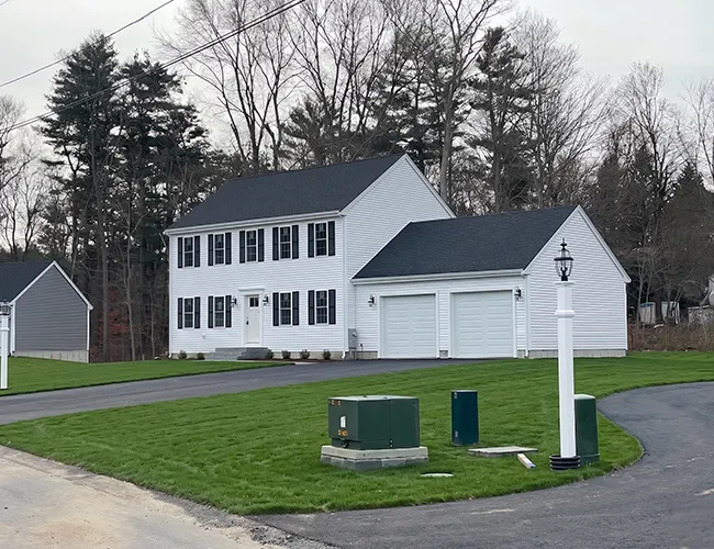 A two-story white house with a double garage and a neatly mowed lawn.