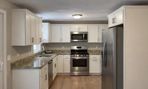 Modern kitchen with white cabinets, stainless steel appliances, and granite countertops.