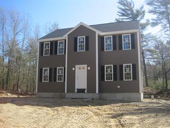 Two-story brown house with white trim and black shutters, surrounded by trees and dirt yard.