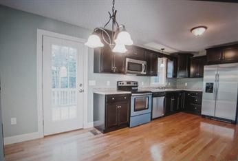 Modern kitchen with dark cabinets, stainless steel appliances, and hardwood floors.