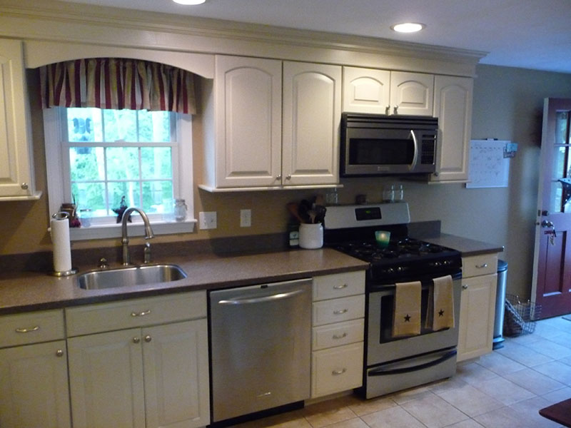 Modern kitchen with white cabinets, stainless steel appliances, and a window above the sink.