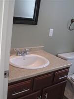 Bathroom vanity with a sink, brown cabinet, and partial view of a toilet and mirror.