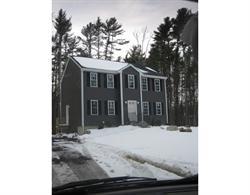 Two-story gray house with white trim, surrounded by snow and tall trees in winter.
