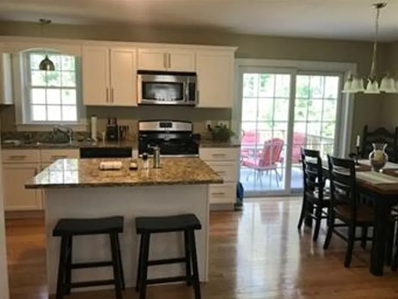 Bright kitchen with island, granite countertops, dining table, and sliding glass doors.