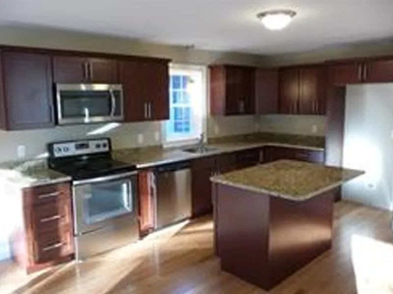 Modern kitchen with dark wood cabinets, granite countertops, and stainless steel appliances.