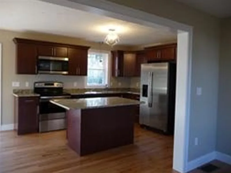 Modern kitchen with dark wood cabinets, island, stainless appliances, and hardwood floor.