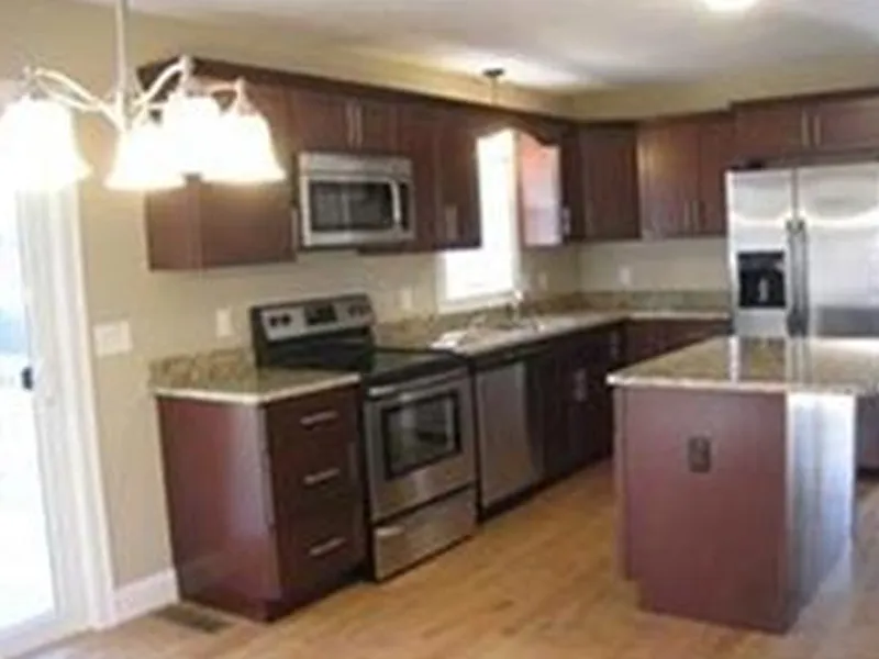 Modern kitchen with stainless steel appliances, brown cabinets, and a central island.
