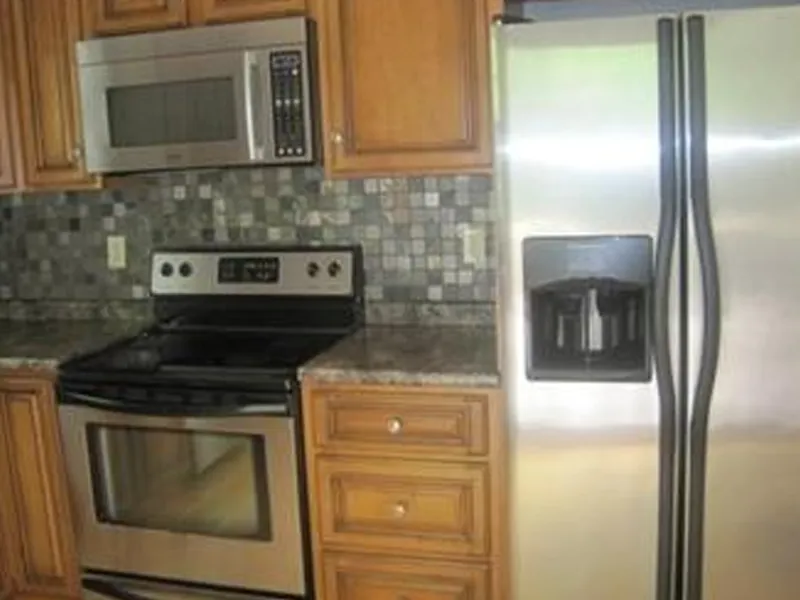 Stainless steel stove, microwave, and fridge in a kitchen with wooden cabinets.