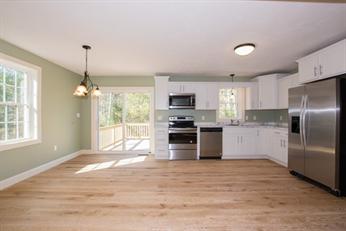 Bright kitchen with white cabinets, stainless steel appliances, and light wood flooring.
