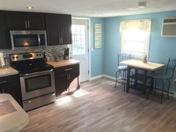 Modern kitchen with stainless steel appliances and a small dining table by a window.