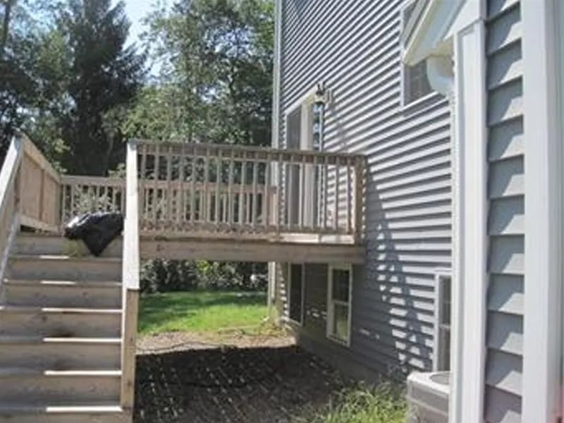 Wooden deck with stairs attached to a gray house, with no door to access the deck.