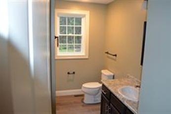 Bathroom with a window, toilet, granite countertop, sink, and light green walls.