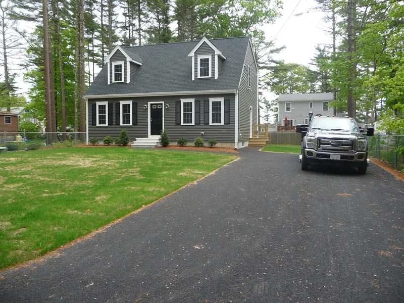 Gray two-story house with dormer windows, black shutters, and a truck in the driveway.