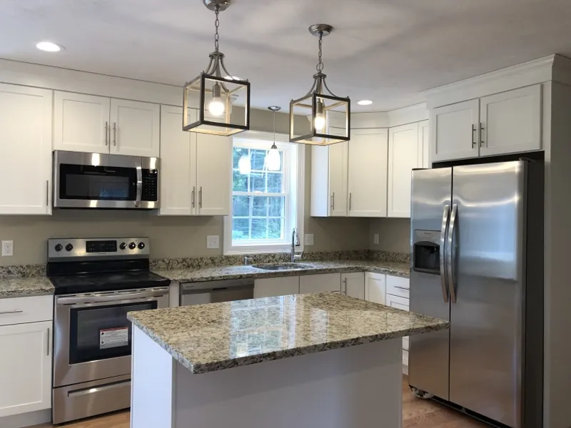 Modern kitchen with white cabinets, granite countertops, and stainless steel appliances.