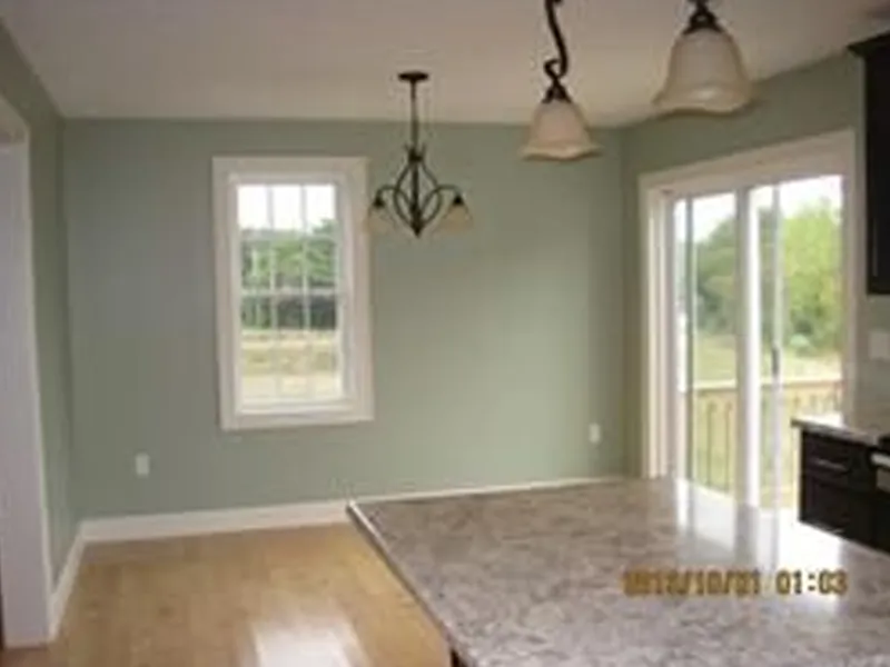 Kitchen with marble countertop, hanging lights, large window, and sliding glass door.