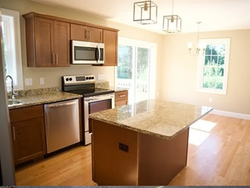 Modern kitchen with wood cabinets, granite countertops, island, and stainless steel appliances.
