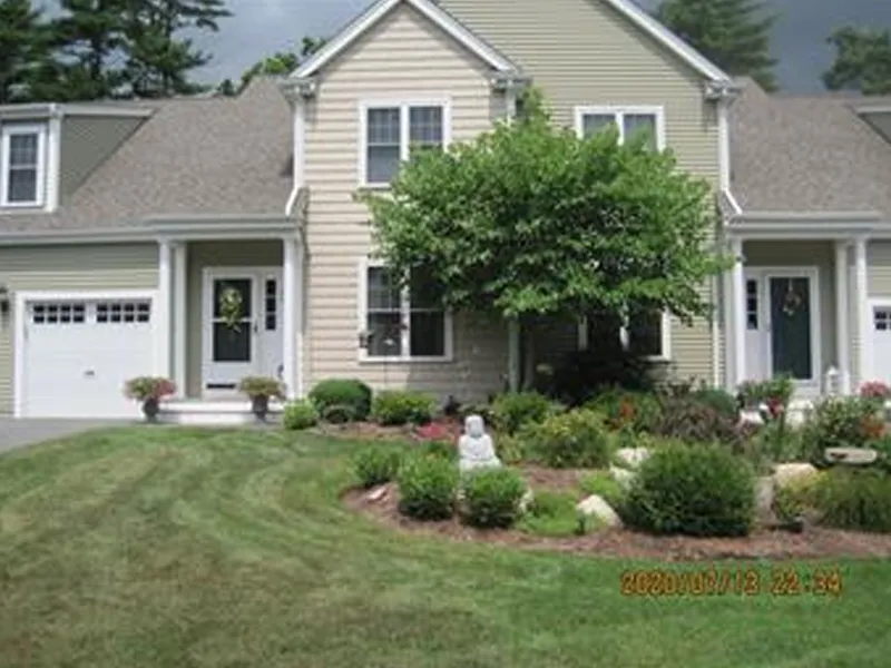 Tan suburban house with a manicured lawn, garden, and small Buddha statue in front.
