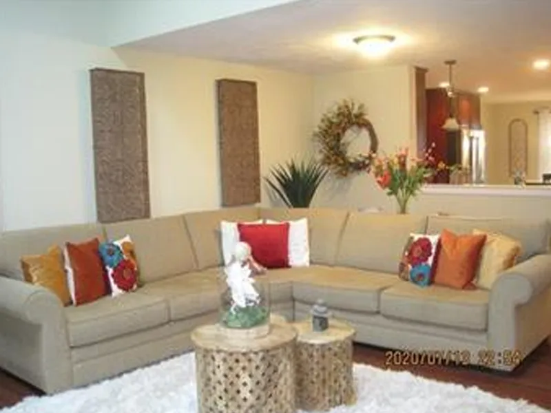 Beige sectional sofa with colorful pillows in a cozy living room with decorative accents.