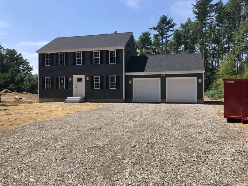 Two-story black house with white trim, double garage, gravel driveway, and trees behind.