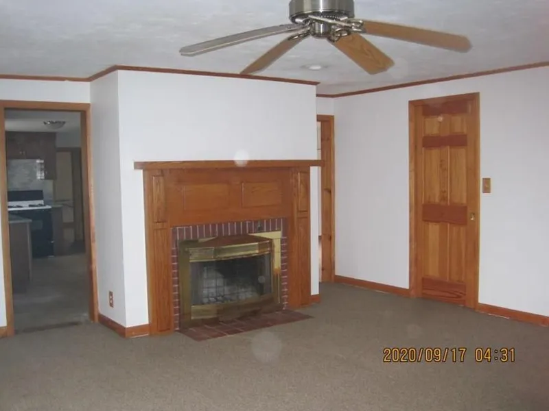 Living room with ceiling fan, fireplace, wood trim, and carpeted floor.