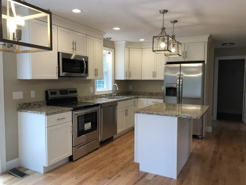 Modern kitchen with white cabinets, stainless steel appliances, and granite countertops.