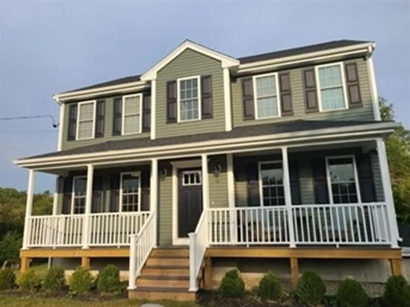 Two-story green house with white trim, black shutters, and a large front porch.