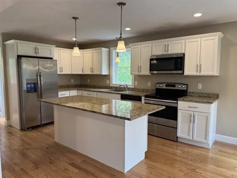 Modern kitchen with white cabinets, granite countertops, and stainless steel appliances.