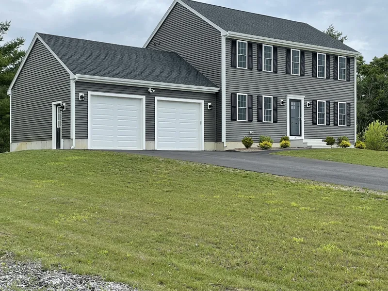 Two-story gray house with white trim and a double garage on a grassy lawn.