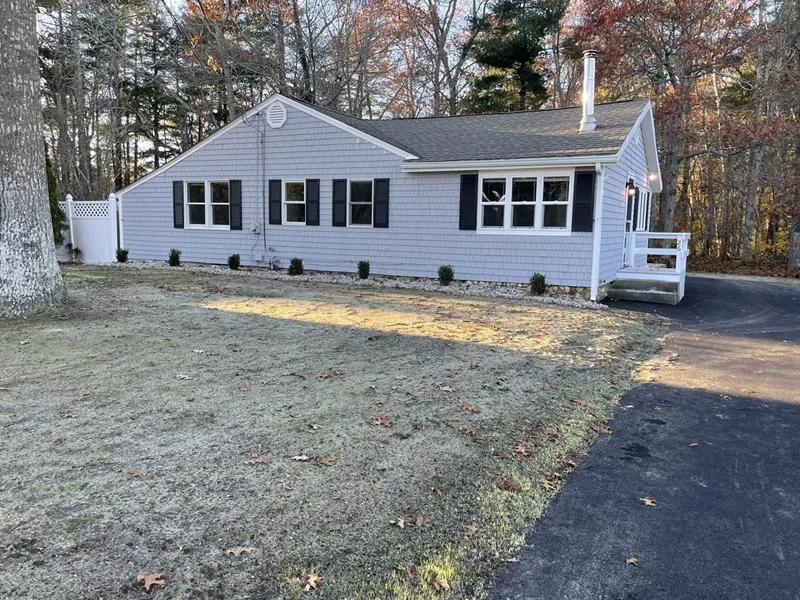 Single-story gray house with black shutters, white trim, and a driveway on a frosty lawn.