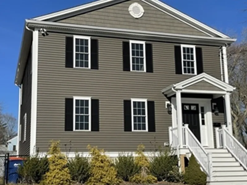 Two-story house with gray siding, black shutters, and a small front porch with stairs.