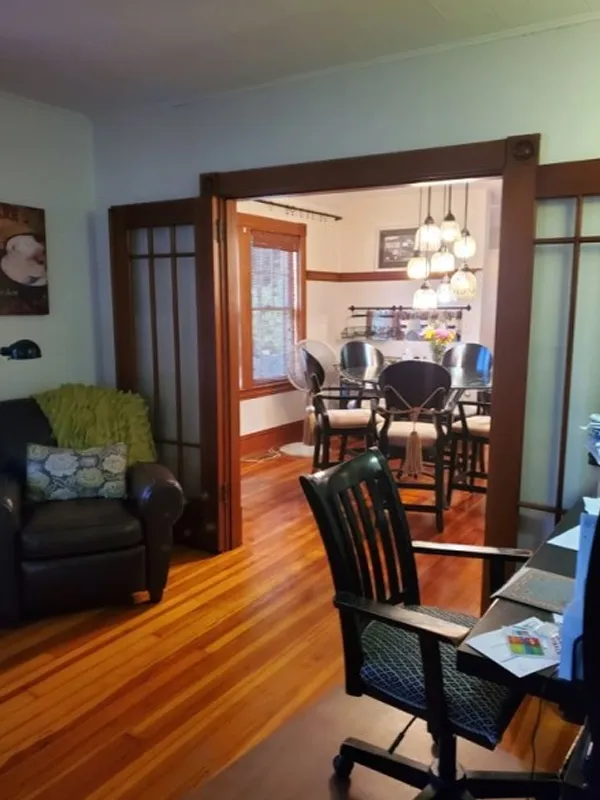 A home office with a desk and chair opens into a dining room with a table and chairs.