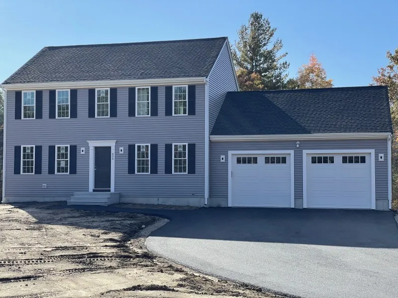 Two-story gray house with white trim, double garage, and a newly paved driveway.