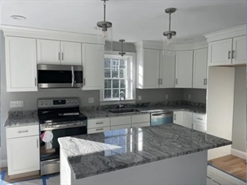 Modern kitchen with white cabinets, stainless appliances, and a gray marble island countertop.