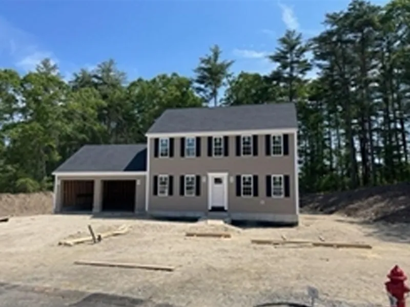 Two-story beige house with black shutters, attached garage, and dirt yard under construction.