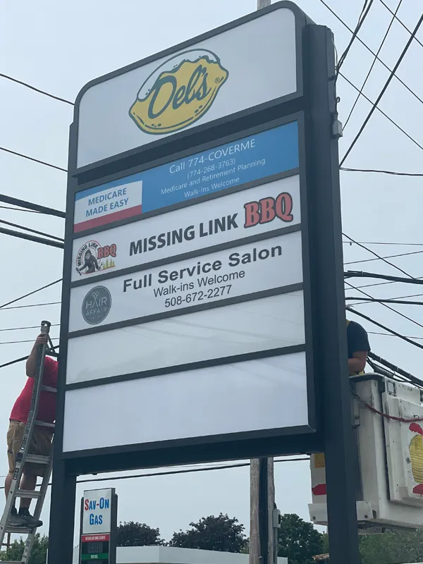 Storefront sign with ads for a BBQ restaurant, salon, and Medicare service; two workers nearby.