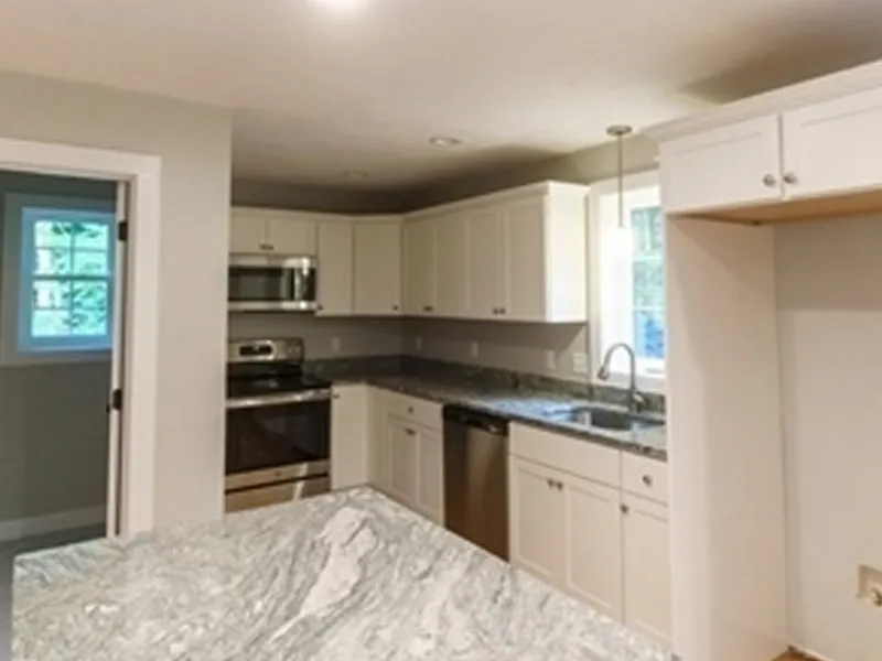 Modern kitchen with white cabinets, stainless steel appliances, and marble countertops.