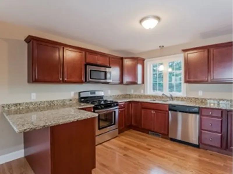 Modern kitchen with cherry wood cabinets, stainless steel appliances, and granite counters.
