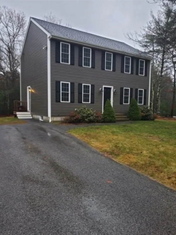 Two-story gray house with black shutters, a driveway, and a small front yard.