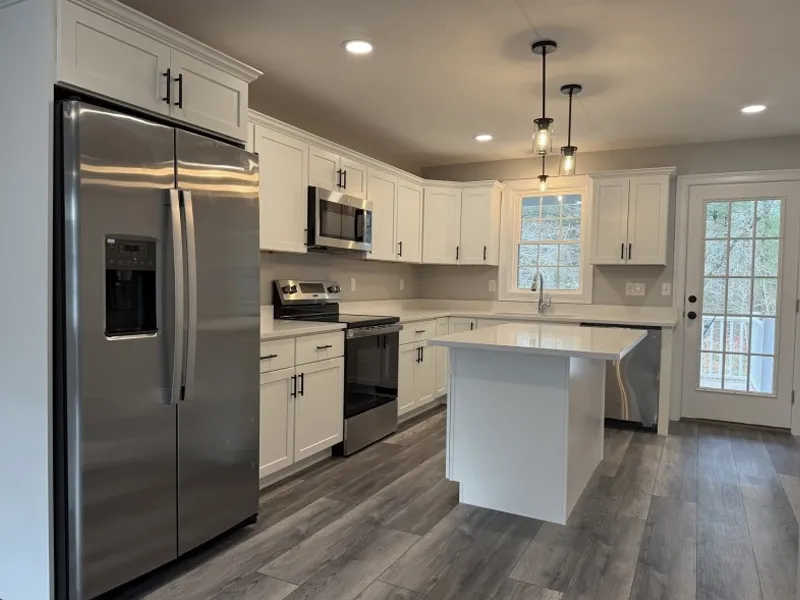 Modern kitchen with white cabinets, stainless steel appliances, and a central island.