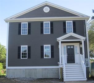 Two-story house with dark siding, white trim, and a front porch with steps.