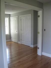 Empty room with hardwood floors, gray walls, and two closed white doors.