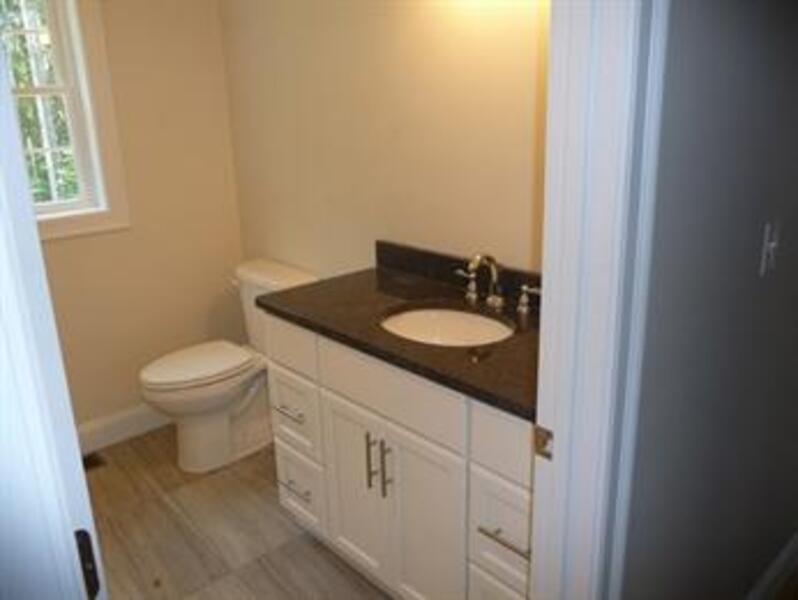 Small bathroom with a toilet, white vanity, black countertop, and a window.