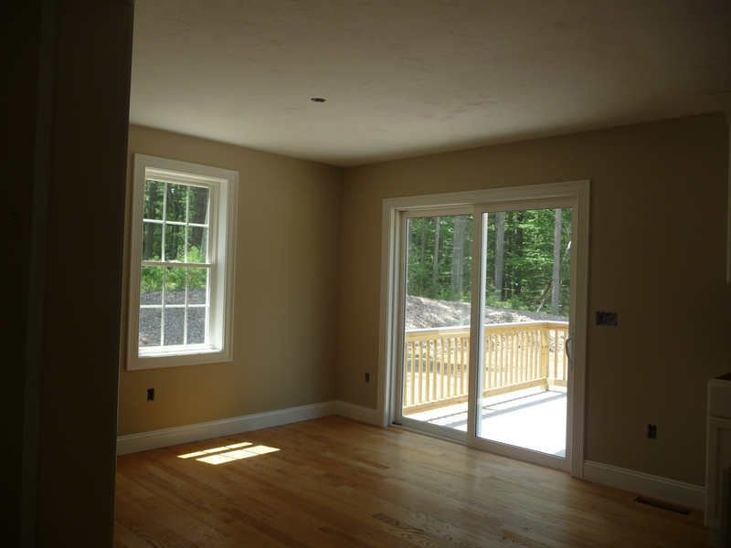 Sunny room with hardwood floors, a window, and a glass door leading to a deck outside.