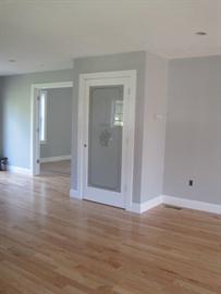 Room with light wood floors, gray walls, and a door with frosted glass and white trim.