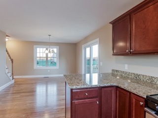 Kitchen with granite countertops, wooden cabinets, and open dining area with large window.