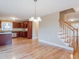 Open kitchen and dining area with wood floors and staircase to the right.