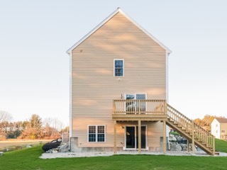 Beige two-story house with an exterior staircase and a grassy yard.