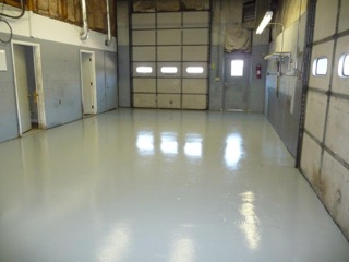 Empty garage with freshly painted, shiny gray floor and closed overhead door.