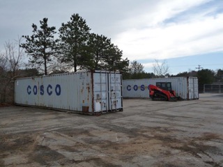 Two large shipping containers labeled COSCO with a red skid steer loader nearby.