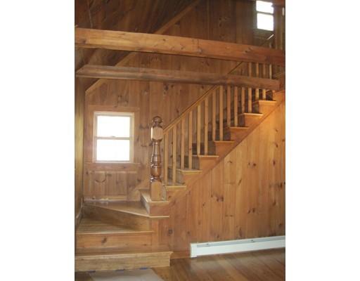Wooden staircase with railing and pine-paneled walls in a rustic interior setting.